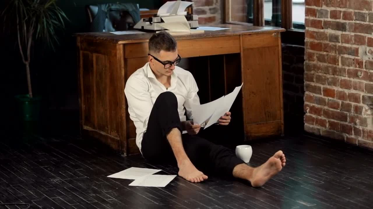 Download Stock Video Barefoot Writer Sits On Floor Reading Manuscript Live Wallpaper For PC