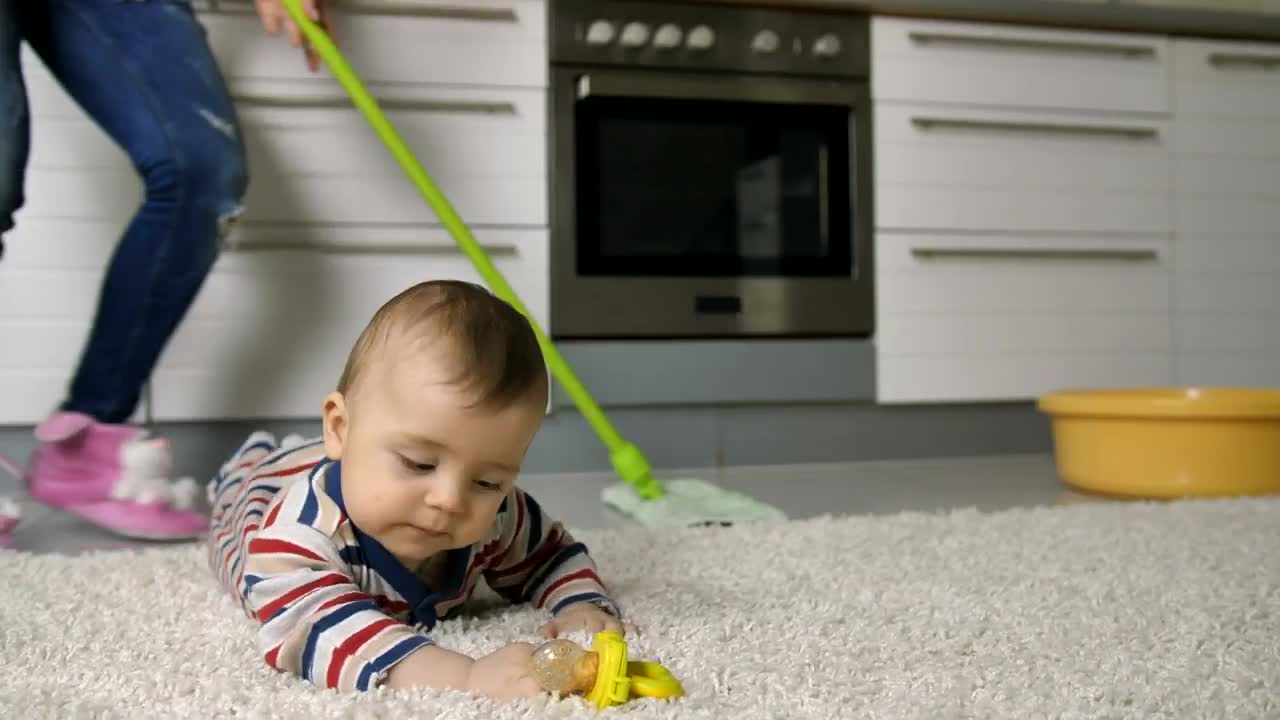 Download Stock Video Baby Lying On A Rug While Her Mother Cleans Behind Live Wallpaper For PC