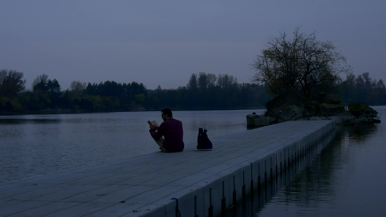 Download Stock Video A Man Reading A Book On A Concrete Pier Live Wallpaper For PC