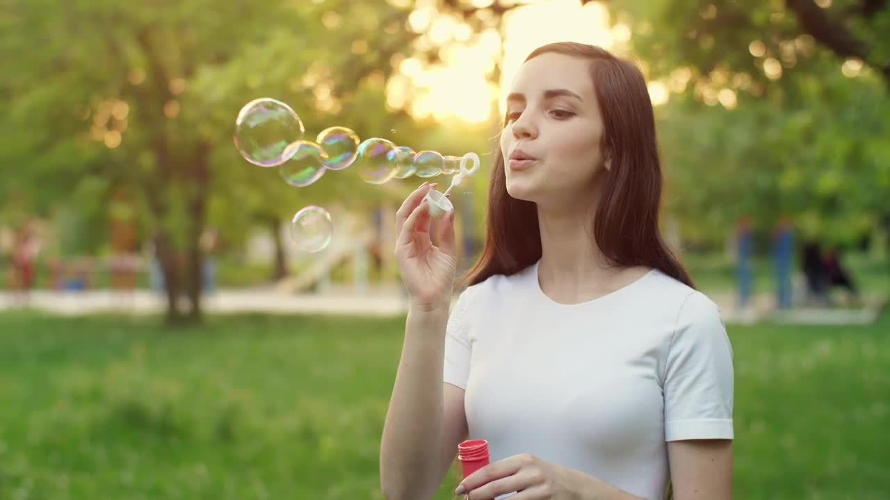 Download Video Stock Cheerful Girl Blowing Soap Bubbles In A Park Live Wallpaper For PC