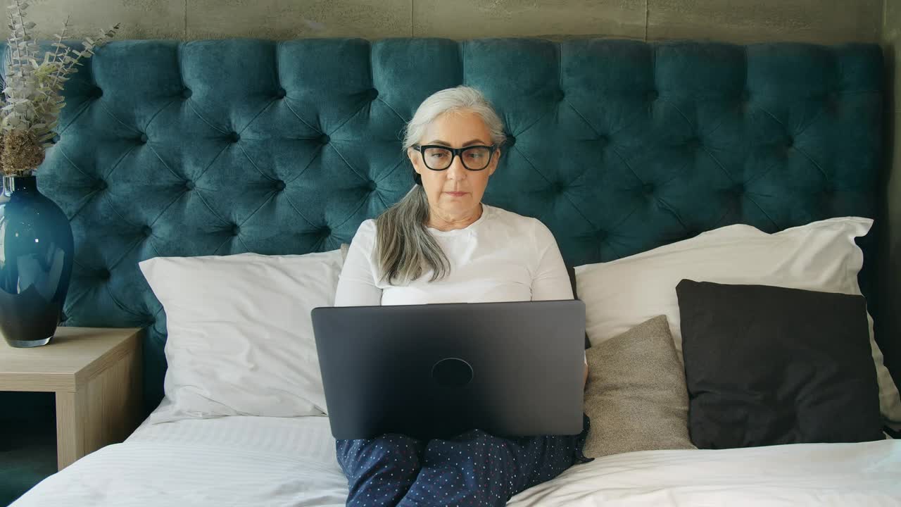 Download Stock Video Elderly Woman On Laptop In Blue Bedroom Live Wallpaper For PC