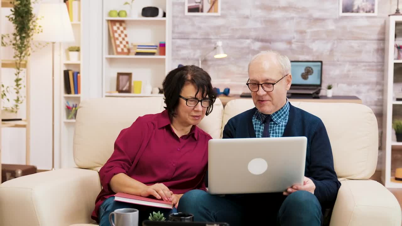 Download Stock Video Elderly Couple On Sofa With Laptop Shopping Online Live Wallpaper For PC