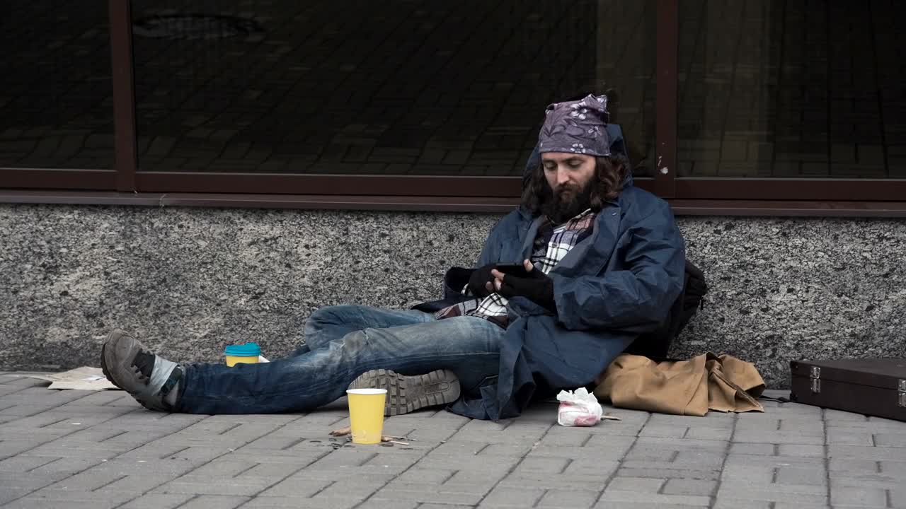 Download Stock Video Homeless Man Using Smartphone On The Street Animated Wallpaper