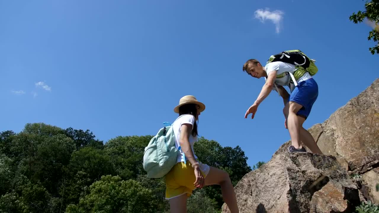 Download Stock Video Hiking Man Helping His Partner Climb Animated Wallpaper