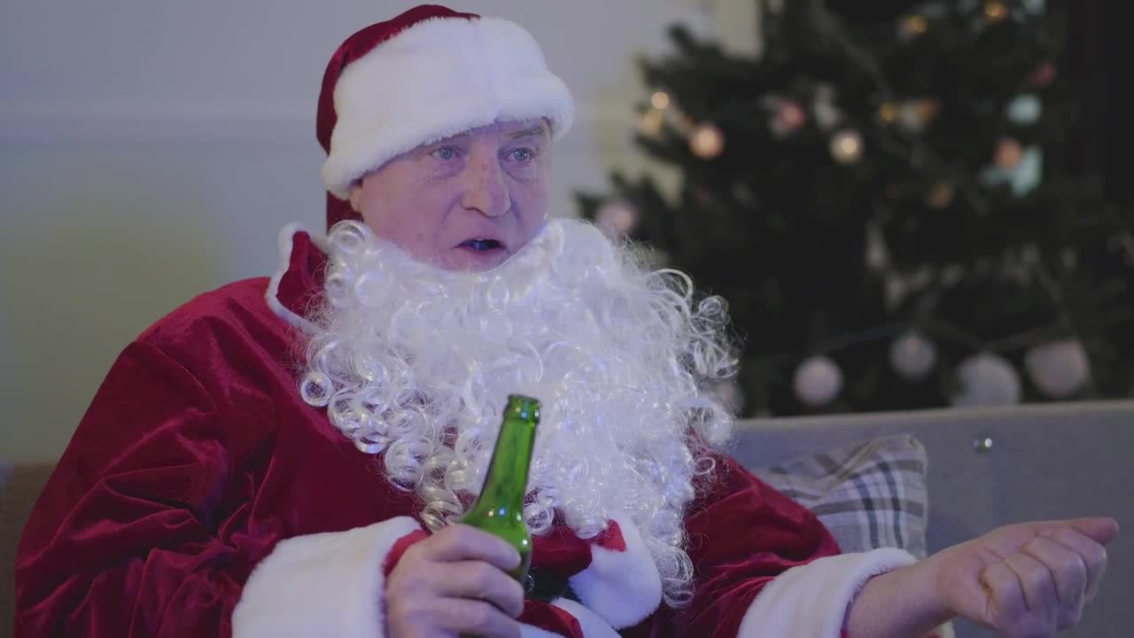 Download Stock Video Man In Santa Costume Drinks Beer On Sofa Animated Wallpaper