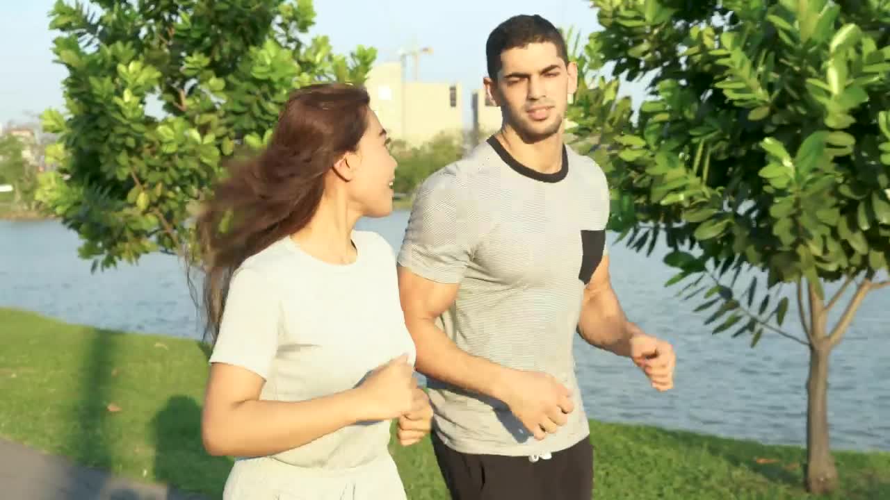 Download Stock Video Man And Woman Running Through A Sunny Park Animated Wallpaper