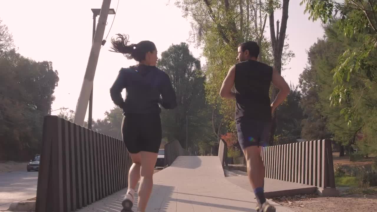 Download Stock Video Man And Woman Jogging Through A Park In The City Animated Wallpaper