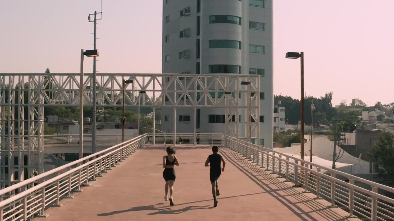 Download Stock Video Man And Woman Exercising On A Pedestrian Bridge Animated Wallpaper