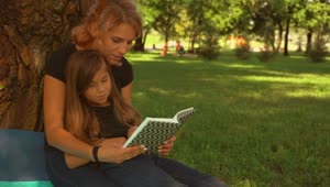 Download Stock Video Mother And Daughter Read A Book Together In A Par Animated Wallpaper