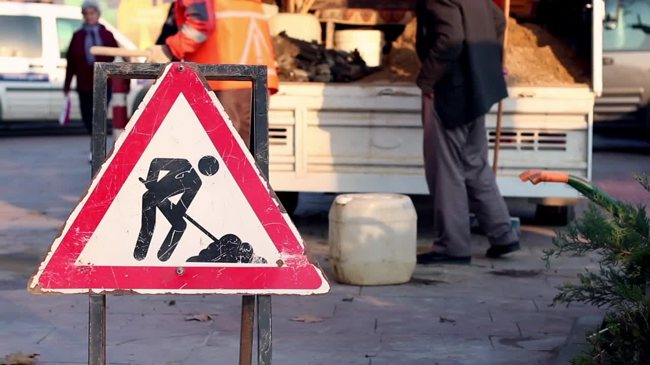 Download Stock Video Men Cleaning A Street With A Dirt Road Sign Animated Wallpaper