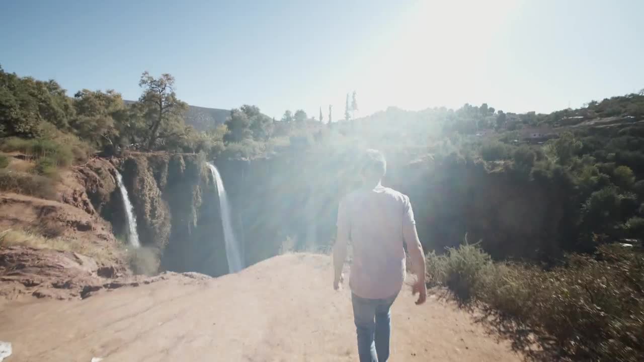 Download Stock Video Man Walks To A Deep Canyon With Waterfall Animated Wallpaper