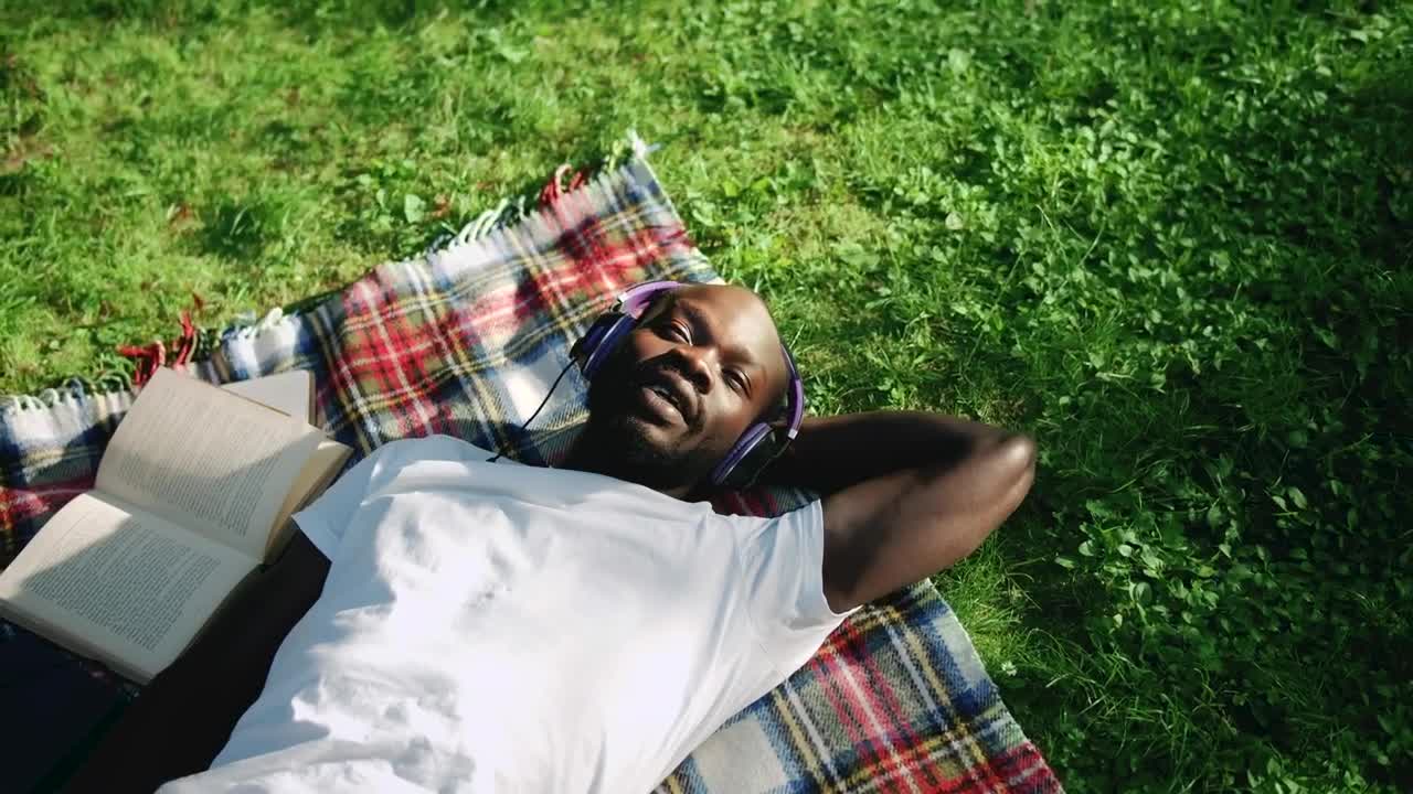 Download Stock Video Man Sings Along To Music Lying In Park With Headphone Animated Wallpaper