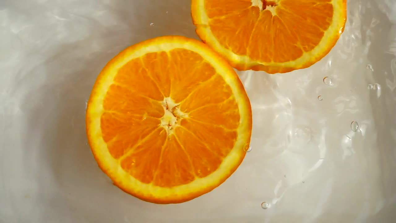 Download Stock Video Orange Half Spinning While Floating In Water Live Wallpaper