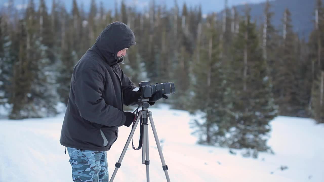 Download Video Stock Photographer And His Tripod Camera In A Snowy Forest Live Wallpaper Free