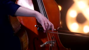 Download Video Stock Playing The Cello With Blurry Lights In The Background Live Wallpaper Free