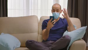 Download Video Stock Quarantined Man Chats On Smartphone On Couch Live Wallpaper Free