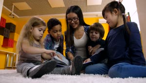 Download Free Video Stock teacher with children reading a book on the carpet Live Wallpaper