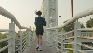 Download Free Stock Video Woman Jogging Across A Narrow Footbridge Live Wallpaper