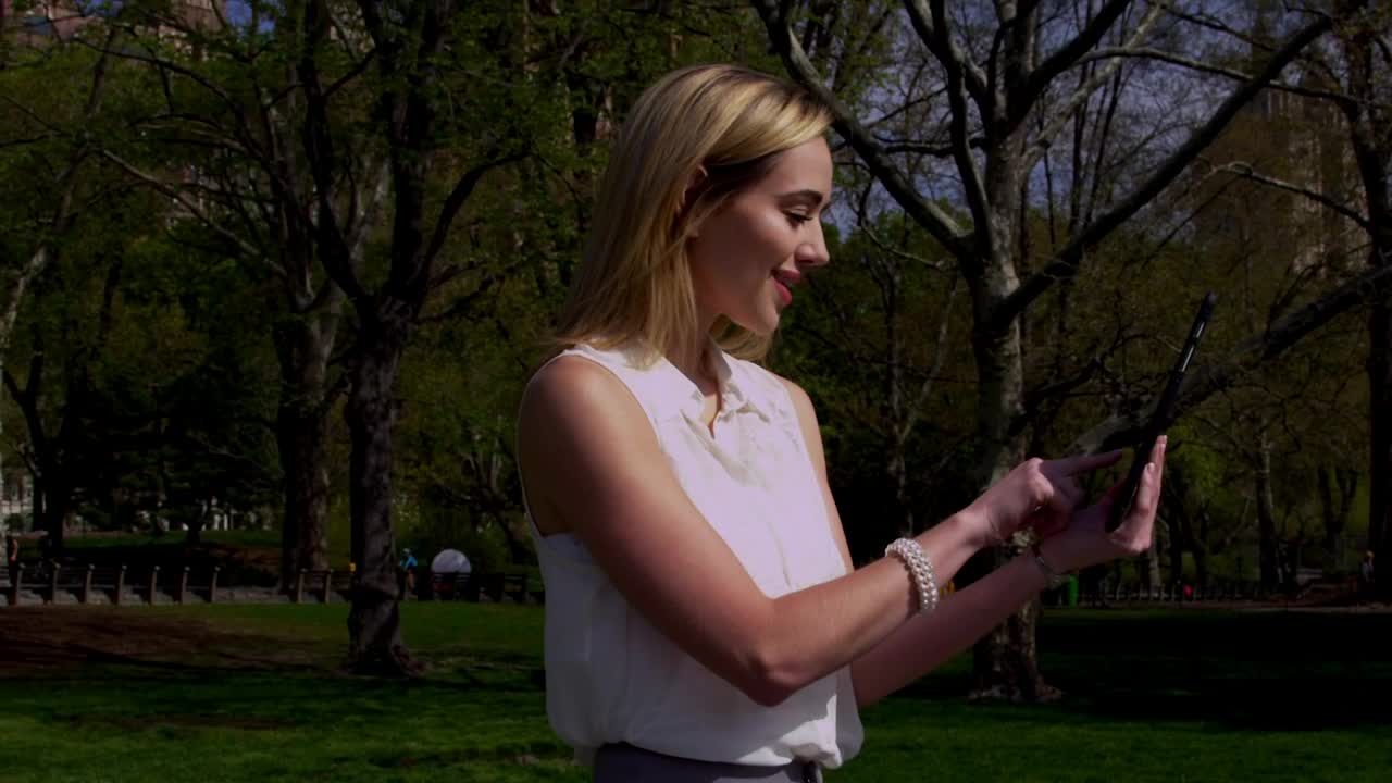 Download Stock Footage Woman Scrolling On A Tablet In Central Park Live Wallpaper Free